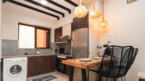 Cocina compacta con lavadora, una mesa de comedor con sillas e iluminación colgante.