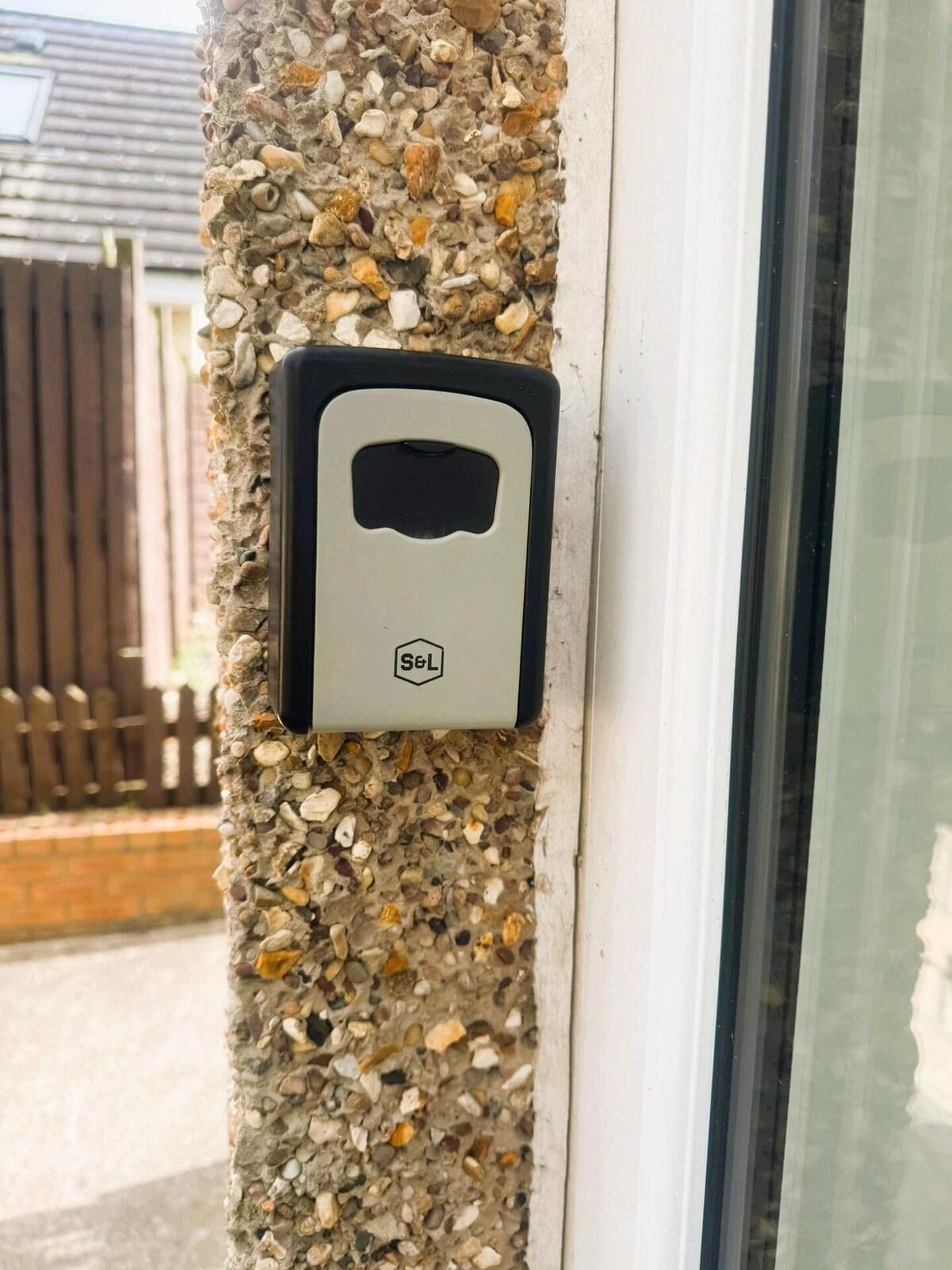 A security device attached to a wall with a rough, pebble-textured surface.