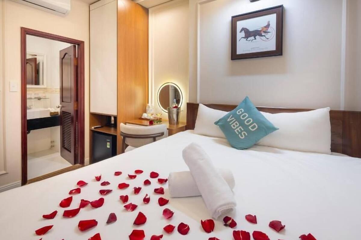Een hotelkamer met een bed, nachtkastje, spiegel en een ingelijst schilderij aan de muur.