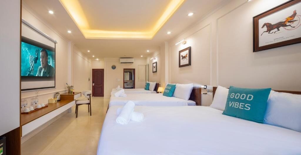 A hotel room with two beds, a TV, a desk with a chair, and a framed picture on the wall.