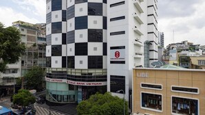 Edifici d'altures múltiples amb façana graella, una entitat bancària pública a la planta baixa i una botiga amb el logotip d'Adidas visible.