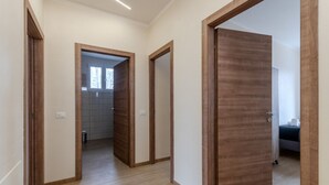 A hallway with wooden doors, a tiled floor, and a visible bathroom with a window. - A bright and welcoming 90 square meters apartment, perfect for seven people, located on the first floor of a building without an elevator.The property is located in Tessera, a suburb close to Marco Polo Airport. The location is also ideal for reaching Ve (Venice)