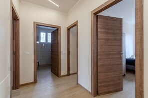 A hallway with wooden doors, a tiled floor, and a visible bathroom with a window. - A bright and welcoming 90 square meters apartment, perfect for seven people, located on the first floor of a building without an elevator.The property is located in Tessera, a suburb close to Marco Polo Airport. The location is also ideal for reaching Ve (Venice)
