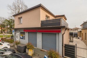 A two-story building with a garage, a red awning, and a small balcony. - A bright and welcoming 90 square meters apartment, perfect for seven people, located on the first floor of a building without an elevator.The property is located in Tessera, a suburb close to Marco Polo Airport. The location is also ideal for reaching Ve (Venice)