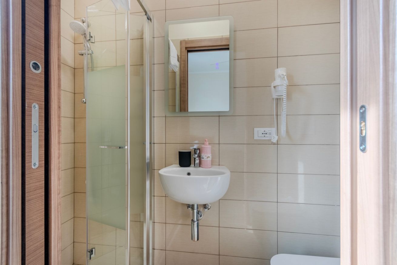 A bathroom with a glass shower enclosure, a white sink, and a mirror.