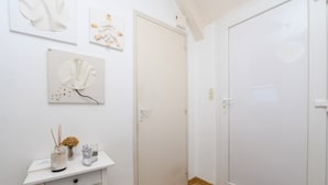 A white room with a wooden floor, a white door, and a white wall with three framed artworks. - Apartment 'Sarzeau City Center on Foot' with Wi-Fi and Air Conditioning (Sarzeau)