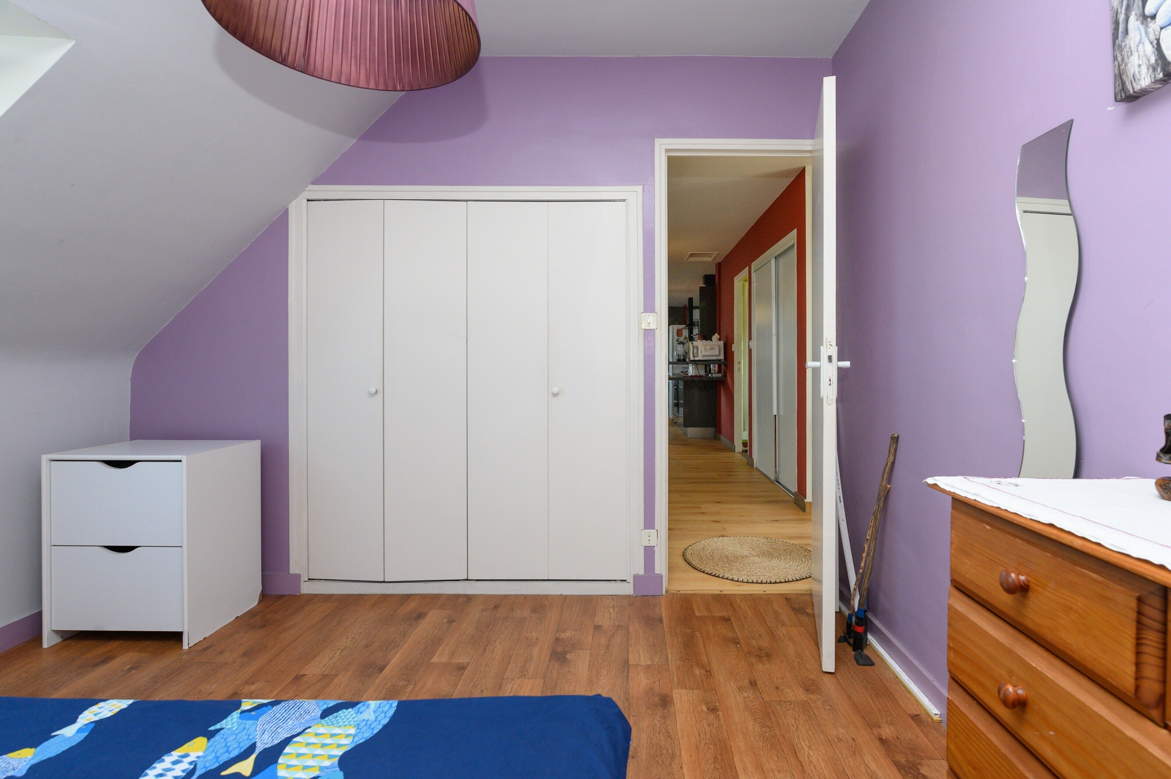Een slaapkamer met een bed, een kledingkast, een dressoir en een spiegel.