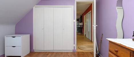 Een slaapkamer met een bed, een kledingkast, een dressoir en een spiegel.