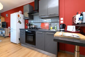 A modern kitchen with stainless steel appliances, a wooden countertop, and red walls. - Apartment 'Sarzeau City Center on Foot' with Wi-Fi and Air Conditioning (Sarzeau)