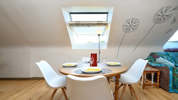 A dining area with a round table, white chairs, and a small side table. - Apartment 'Sarzeau City Center on Foot' with Wi-Fi and Air Conditioning (Sarzeau)