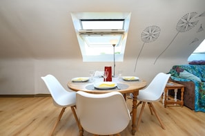 A dining area with a round table, white chairs, and a small side table. - Apartment 'Sarzeau City Center on Foot' with Wi-Fi and Air Conditioning (Sarzeau)