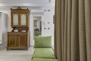 Une pièce avec un meuble en bois, un canapé vert et un rideau.