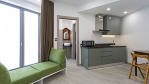Un apartamento moderno con un sofá verde, una cocina con microondas y una zona de comedor.