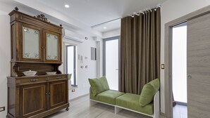Una habitación con un armario de madera, un sofá verde y un ventanal con cortinas.