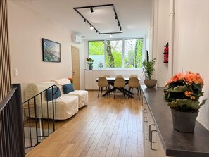 Ein modernes Interieur mit Essbereich, einer Couch, einer Treppe und einem Blumentopf.