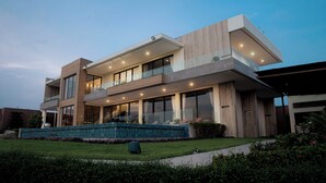 Una moderna casa a due piani con un balcone, ampie finestre e una piscina.