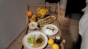 A wooden tray with breakfast items including eggs, toast, and a drink, placed on a bed.