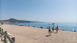A beach with people, umbrellas, and boats. - Luminous apartment with two balconies and swimming pool in front of the sea (Blanes)
