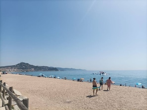 Ein Strand mit Menschen, Sonnenschirmen und Booten.