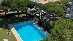 A swimming pool with people, a beach, and a view of the sea. - Luminous apartment with two balconies and swimming pool in front of the sea (Blanes)