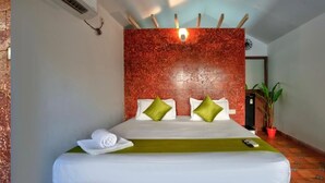 Habitación de hotel con una cama, aire acondicionado de pared, un reloj y una planta en maceta.
