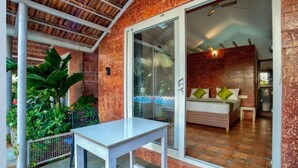 Una habitaci ón con cama, una mesa y un vidrio que da a un balcón.