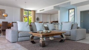Een moderne woonkamer met grijze banken, een houten salontafel en een groot raam.