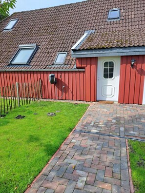 A red building with a white door, a small window, and a skylight. - Seagull's nest in the middle of the countryside (Dornum)