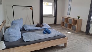 A modern bedroom with a wooden bed, a bedside table, a radiator, a window with curtains, and a small wooden cabinet. - Seagull's nest in the middle of the countryside (Dornum)