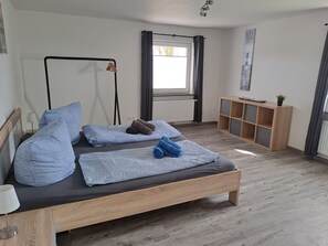 A modern bedroom with a wooden bed, a bedside table, a radiator, a window with curtains, and a small wooden cabinet. - Seagull's nest in the middle of the countryside (Dornum)