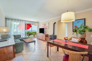 Ein Wohnzimmer mit einer Couch, einem Couchtisch, einem Fernseher und einem Esstisch mit Stühlen.