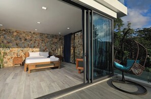 A modern bedroom with a bed, a glass door leading to a balcony, and a hanging chair. - Sugar | Kamala Beach | 4-bedroom Pool Villa (Kamala)