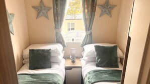 A bedroom with two beds, a nightstand, a lamp, and star decorations on the wall. - Seaside Escape in Wemyss Bay (Wemyss Bay)