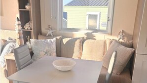 A dining area with a white table, cushioned seating, and decorative items. - Seaside Escape in Wemyss Bay (Wemyss Bay)