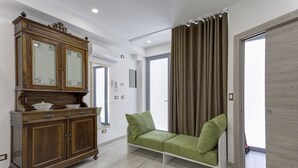 A room with a wooden cabinet with mirrored doors, a green sofa, and a large window with curtains. - Varenna Garden by Wonderful Italy (Perledo)