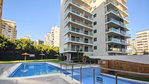 Une piscine avec un poste de surveillance pour les sauveteurs, entourée d’immeubles d’habitation.
