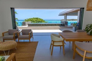 Ein modernes Wohnzimmer mit Meerblick, einem Essbereich und einem Poolbereich mit Grill.