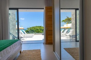 A bedroom with a bed, a view of a pool and lounge chairs, and a door leading to an outdoor area. - Blue Bay Luxury Penthouse offers stunning seaview and direct beachfront access. (Blue Bay)