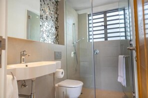 A modern bathroom with a glass shower enclosure, a white sink, and a toilet. - Blue Bay Luxury Penthouse offers stunning seaview and direct beachfront access. (Blue Bay)