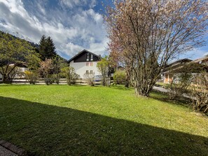 A house with a sloped roof, surrounded by a well-maintained lawn and trees.