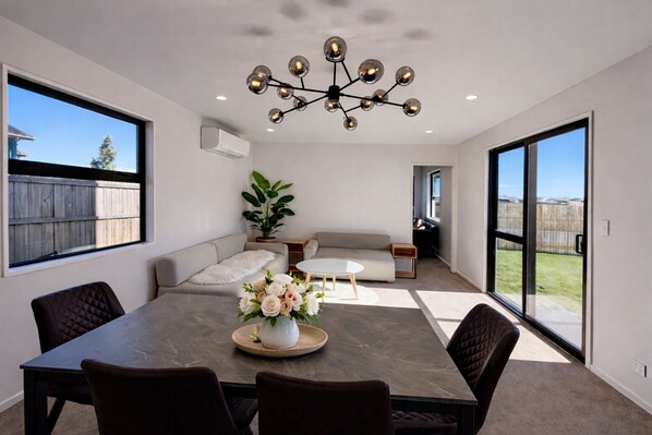 A spacious living room with a dining table, sofa, and a chandelier.
