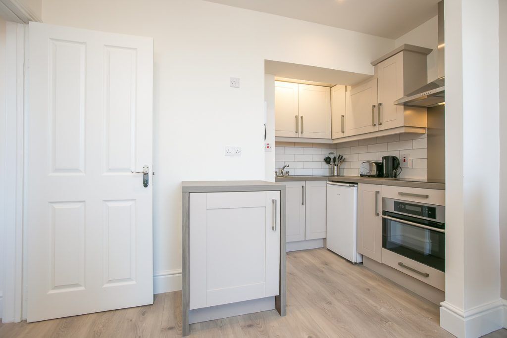 A kitchen with white cabinets, a countertop, and a built-in oven.