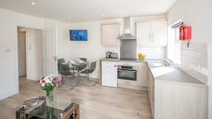 A modern kitchen with white cabinets, a built-in oven, and a stainless steel range hood.