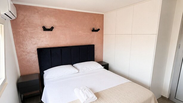 Habitación de hotel con cama, mesita de noche, armario y una lámpara en el techo.