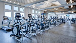 Een sportschool met loopbanden en fitnessapparatuur, grote ramen en een modern plafondontwerp.