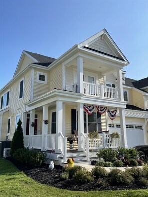 A two-story house with a front porch, a garage, and a well-maintained garden.