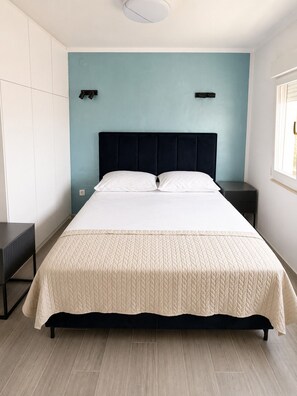 Ein Bett mit einer gesteppten Decke, einem dunklen Kopfteil und zwei Nachttischen.