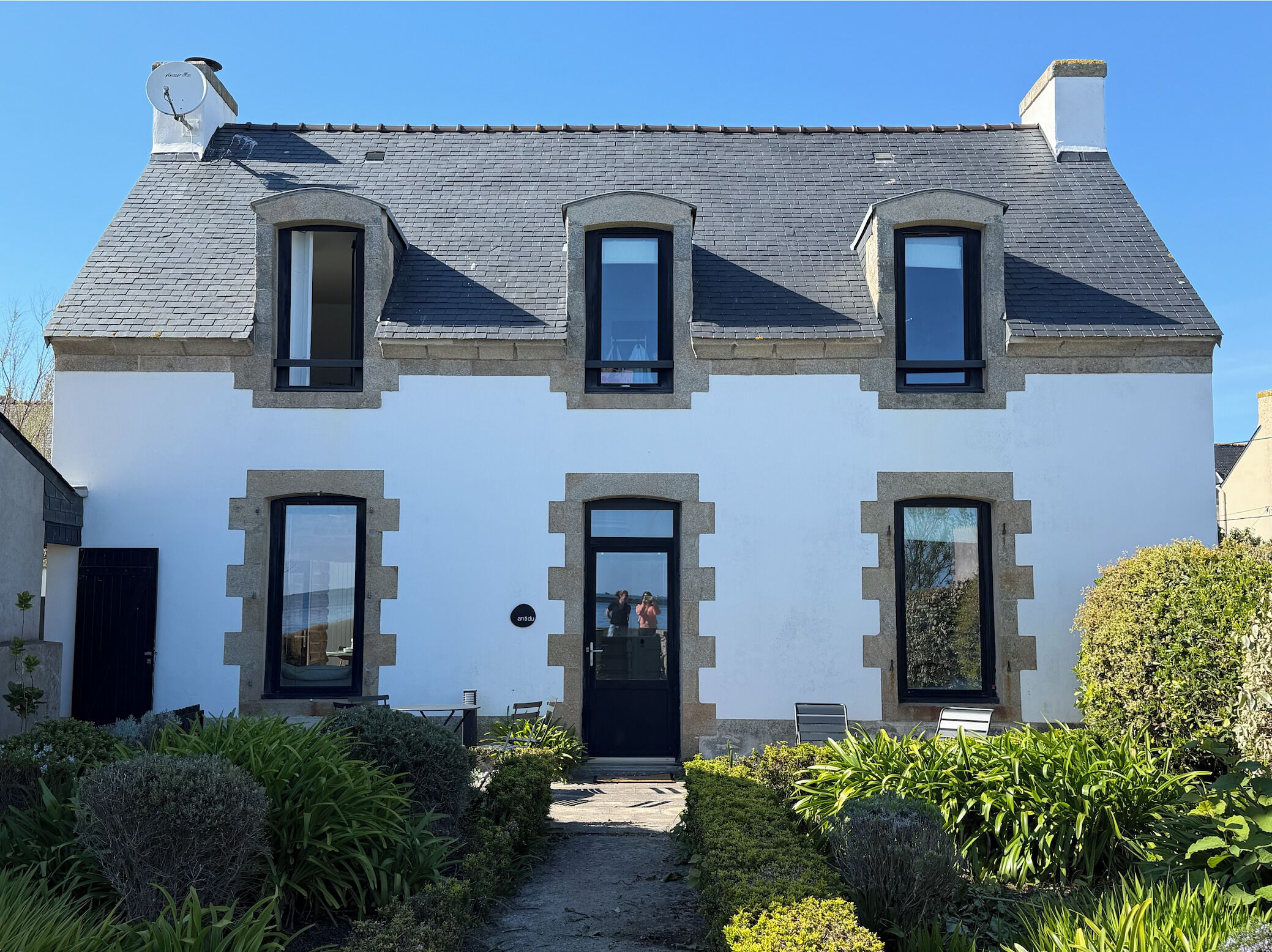 Een herenhuis met twee verdiepingen, een symmetrische voorgevel, een centrale ingang en een kleine tuin.