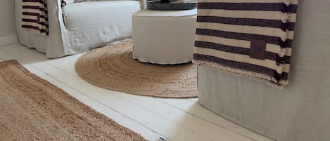 A living room with a sofa, ottoman, and striped throw.