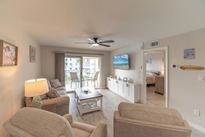Ein Wohnzimmer mit Deckenventilator, einem Essbereich und Blick auf den Balkon.